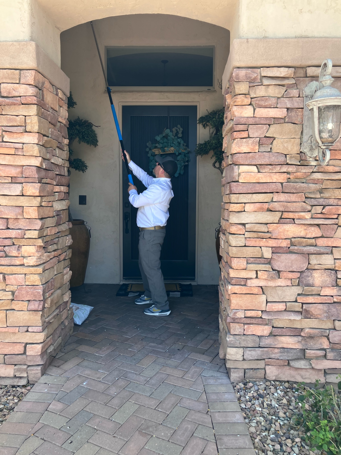 Matt clearing cobwebs and spider nests at a Mesa front door