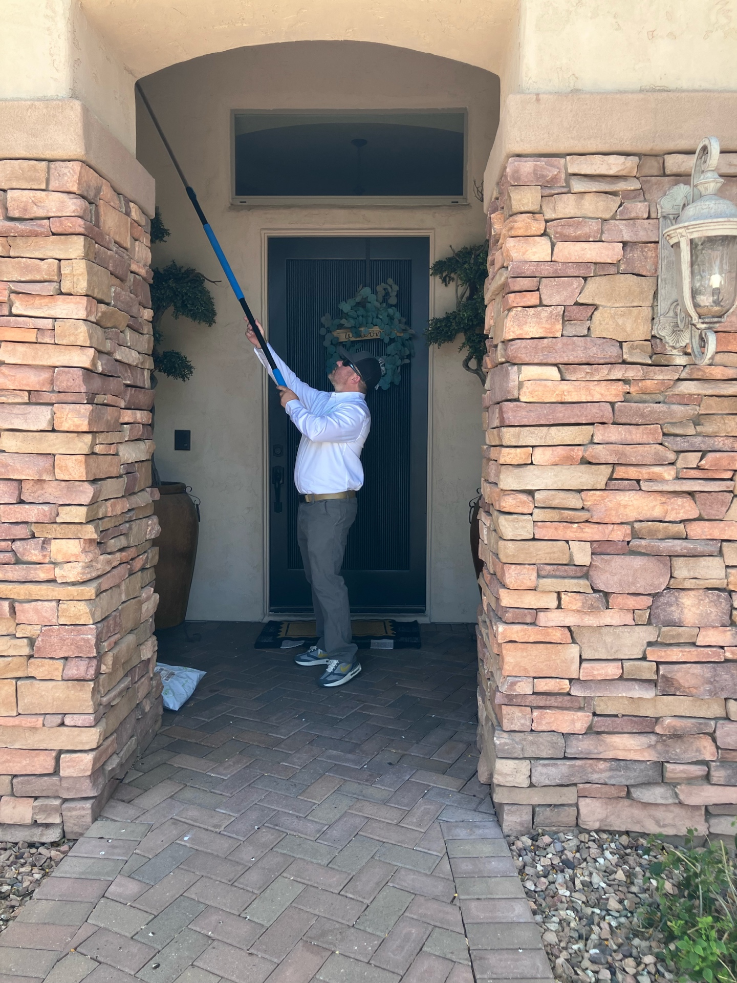 Matt clearing cobwebs and spider nests at a Mesa stone front door